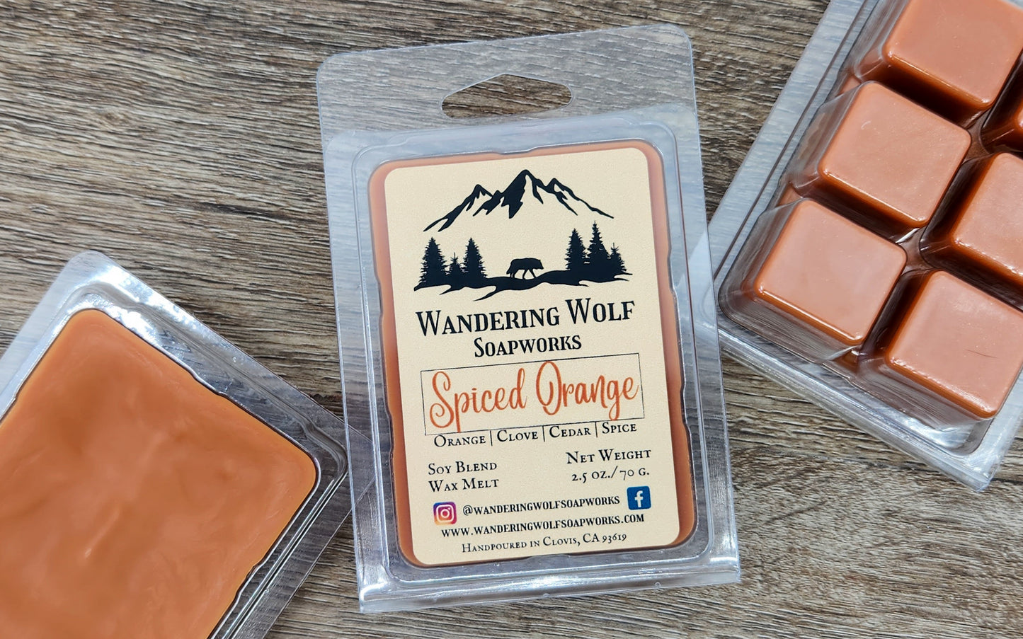 Six orange wax melts in a clear plastic clamshell package with 'Wandering Wolf Soapworks, Spiced Orange' label visible.