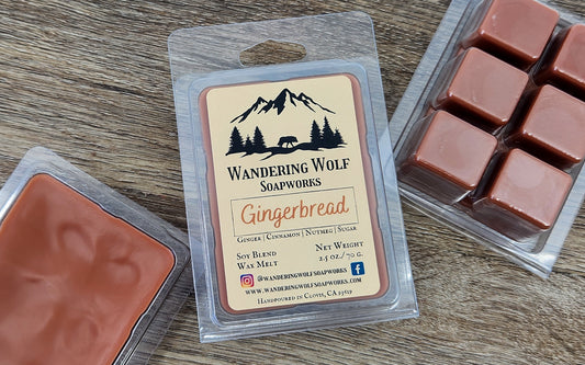 Six brown wax melt cubes in a clear plastic clamshell packaging with a label that reads 'Wandering Wolf Soapworks Gingerbread'. The packaging has an image of a mountain in the background.