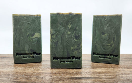 Three bars of green soaps, stamped with Wandering Wolf Soapworks on a wooden surface with a white background