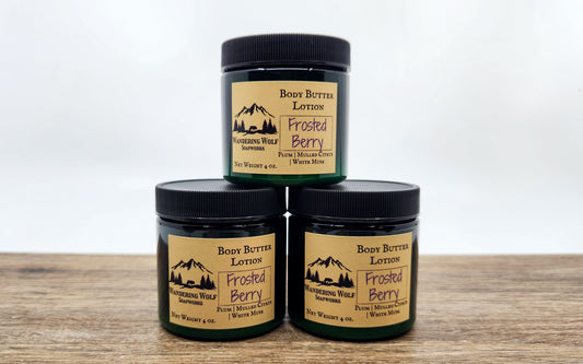 Three jars of 'Frosted Berry' body butter lotion on a wooden surface with a white background.